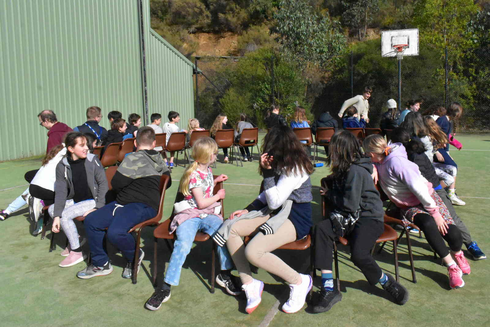 Sitting on chairs in a circle as people run around